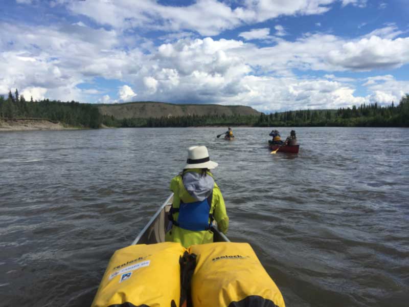 Kayak dry bag being rolled and clipped on the water with D-rings attached to deck lines